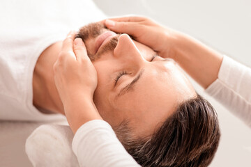 Closeup of middle aged man getting healing face massage at luxury spa. Spa therapist making...