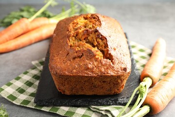 Tasty carrot cake and vegetables on grey textured table, closeup