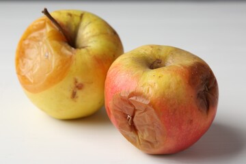 Rotten apples on white wooden table, closeup