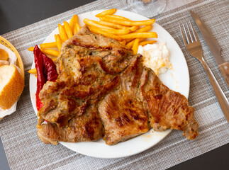 Appetizing grilled pork escalope with side dish of fried potatoes and baked pepper served with cream cheese dip..
