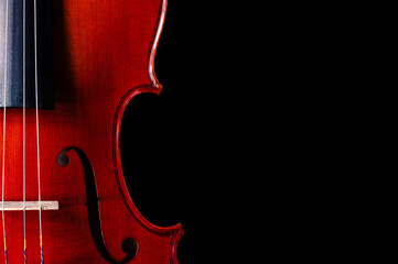 A close-up of the right side of a violin on a black background with copy space on the right © MeganKobe