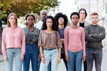 Obraz premium Multiethnic tean of protestors striking against racism on the street. International group of young people making riot next to government building. Racism, discrimination, equality concept