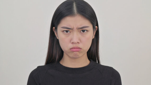 Young asian woman with a displeased expression, looking directly at the camera, portrait