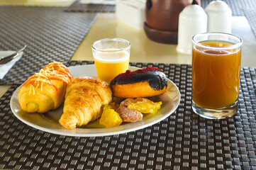 the dishes on the table with plates consist of donuts, croissants, pudding and the typical Indonesian drink kunir asem