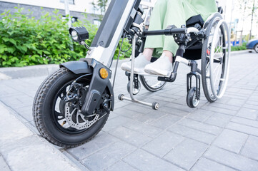 A faceless woman in a wheelchair with an assistive device for manual control. Electric handbike. 