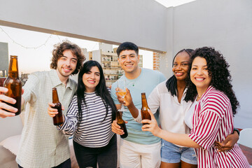 Young Latino men and women embrace and pose for the camera at a rooftop party