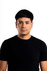 Fototapeta premium Portrait of a young Latin man looking seriously at the camera, dressed in black with a white background