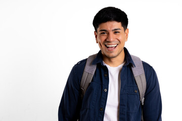 Young Latin man, carrying a backpack, looking at the camera, laughing with his mouth open in a white setting