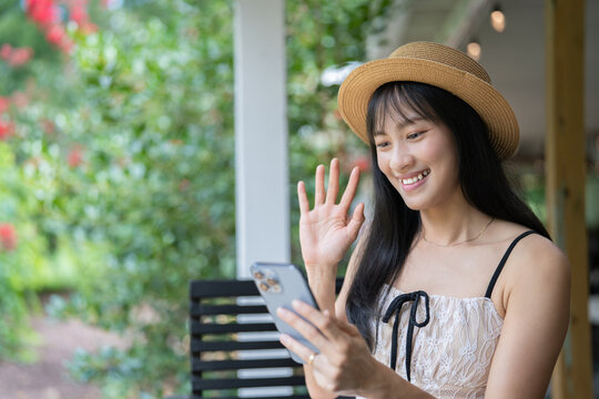 Happy Asian Woman Video Calling and Texting on Smartphone While Traveling.