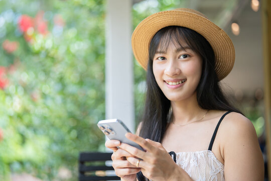 Happy Asian Woman Video Calling and Texting on Smartphone While Traveling.