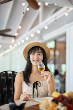 Elegant Asian Woman Savoring White Wine at a Scenic Winery.