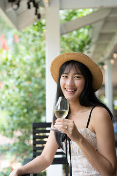 Elegant Asian Woman Savoring White Wine at a Scenic Winery.