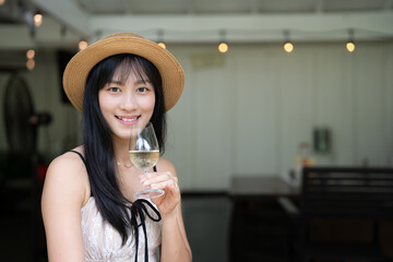 Elegant Asian Woman Savoring White Wine at a Scenic Winery.