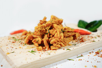 Crispy fried chicken skin with spicy seasoning, chili and lime leaves on wooden cutting board