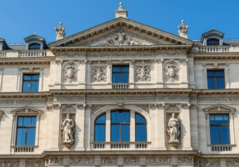 Obraz premium Facade of an ornate building with sculptures and blue windows on a sunny day