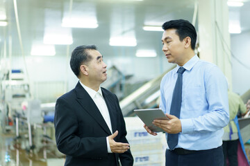 Asian engineer and manager inspect steam pipes and boiler system in a food manufacturing factory.
