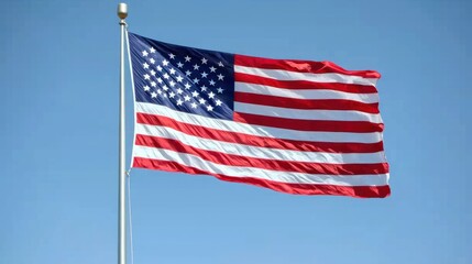 Obraz premium USA flag with stars and stripes flying against a clear blue sky.