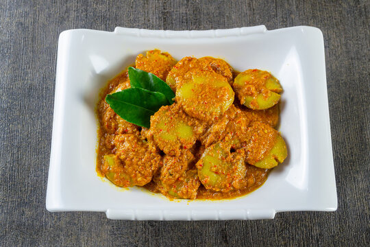 Rendang Jengkol served on a white plate,  popular Indonesian dish made from jengkol cooked in a rich, spicy coconut milk sauce.