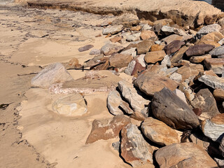 sandstone rocks on sand at the beach after storm, natural coastal erosion in Australia