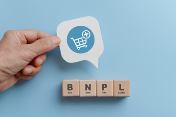 BNPL, buy now pay later, on wooden cube blocks and hand hold  real white speech bubble paper cut...
