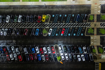 Cars parked in a crowded urban parking lot, under a clear blue sky.