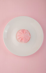 Pastel-colored marshmallows on white plate over pink background, sweet candy arrangement with soft colors and copy space