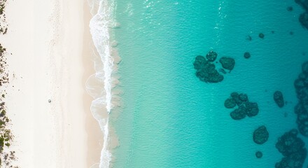 Aerial view of gentle waves meeting a pristine sandy beach and clear turquoise water