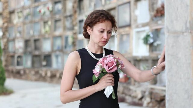  Woman brought flowers to the cemetery and cries over the death of a beloved relative