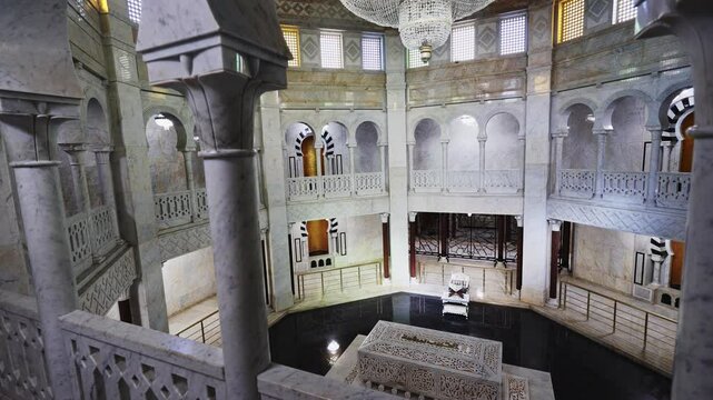 Central hall and interior of mausoleum of Habiba, Tunisia. Tomb of president is decorated with white marble, columns, and tiles. In center of first floor there is tomb and throne