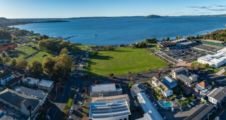 Aerial view of people enjoying a sunny day at Rotorua Lakefront Reserve, a popular park with walking paths, playgrounds, and lake access in New Zealand.