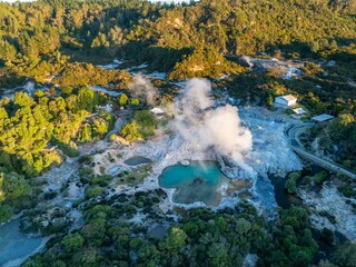 Aerial view of the Te Puia geothermal park in Rotorua, New Zealand. Tourists walk along the boardwalk to view the geysers and hot springs. The park is a popular tourist destination.