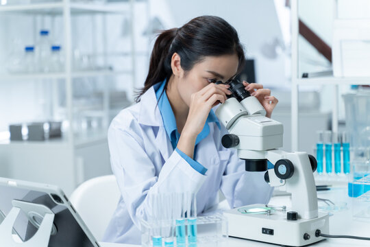 Asian Researcher using a microscope in the clinical lab.Female Researcher working in the clinical laboratory,Medical or scientific researcher or Asian woman doctor looking at professional microscope.