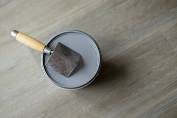 The spatula for the corners lies on top of the jar with putty. Laminated grey background. Repair...