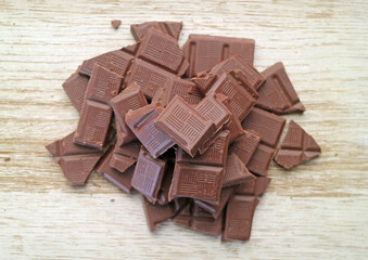 Pile of chocolate chunks isolated on wooden background