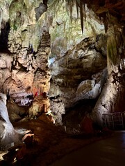 Visitors explore a captivating cave adorned with intricate limestone formations and colorful lighting, showcasing nature's beauty and geological wonders on a guided tour