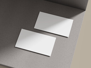 Business card mockup lying on a soft cement block surface with natural light, creating a relaxed and professional look.