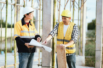 Engineers and contractors discussing blueprints on construction site—teamwork, safety, and...