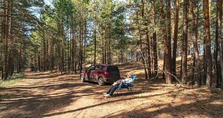 old woman sitting in arm chair in the forest
