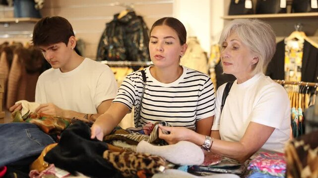 Shoppers carefully sift through thrift shop's clothing collection, searching for pieces to their wardrobes. High quality 4k footage