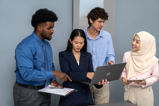 Diverse team collaborating on project in office, african, asian and muslim professionals discussing data use laptop and tablet, teamwork, modern workplace, corporate meeting business strategy