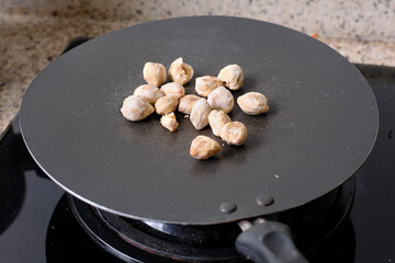 closeup shot of some candlenuts on hot frying pan to dry
