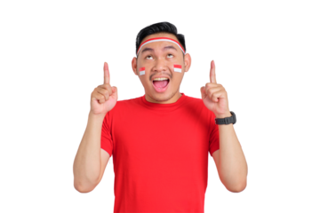 Shocked young Asian man celebrating Indonesian independence day pointing fingers up at copy space isolated on transparent background