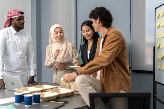Diverse team discussing eco-friendly packaging, sustainability meeting with paper trays, multicultural group brainstorming green product ideas, corporate collaboration, environmental responsibility