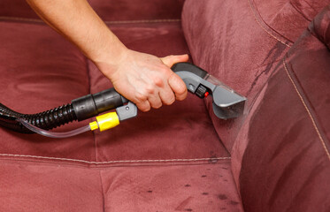 A person is cleaning a couch with a steam cleaner