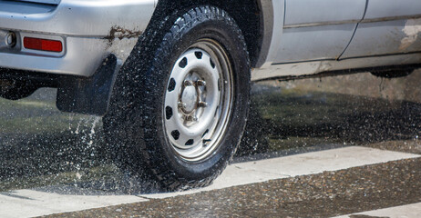 A truck is driving down a wet road with water spraying out from the back