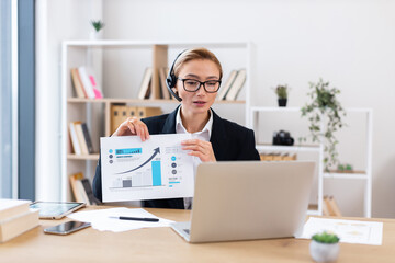 Professional businesswoman in her 30s showcasing chart during video conference call in office.