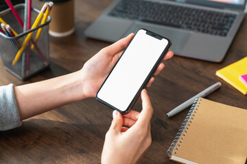 Hand holding smartphone with a blank screen on table, for putting advertising to promote.