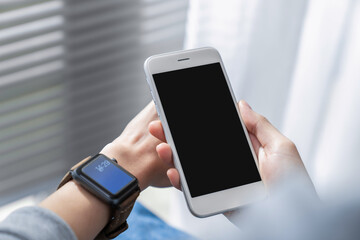 Hand holding smartphone with a blank screen on table, for putting advertising to promote.