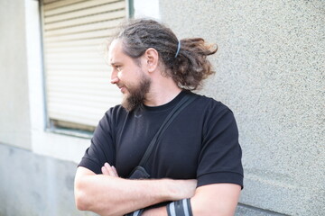 Security guard looking away with folded arms by a wall