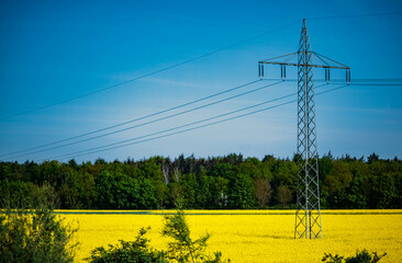 high voltage pole against rapeseed field